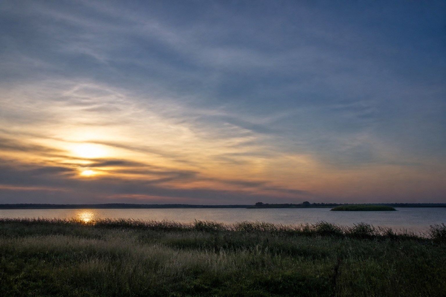 Low northern horizon over meadows and water at evening, suggesting a five-day westbound line